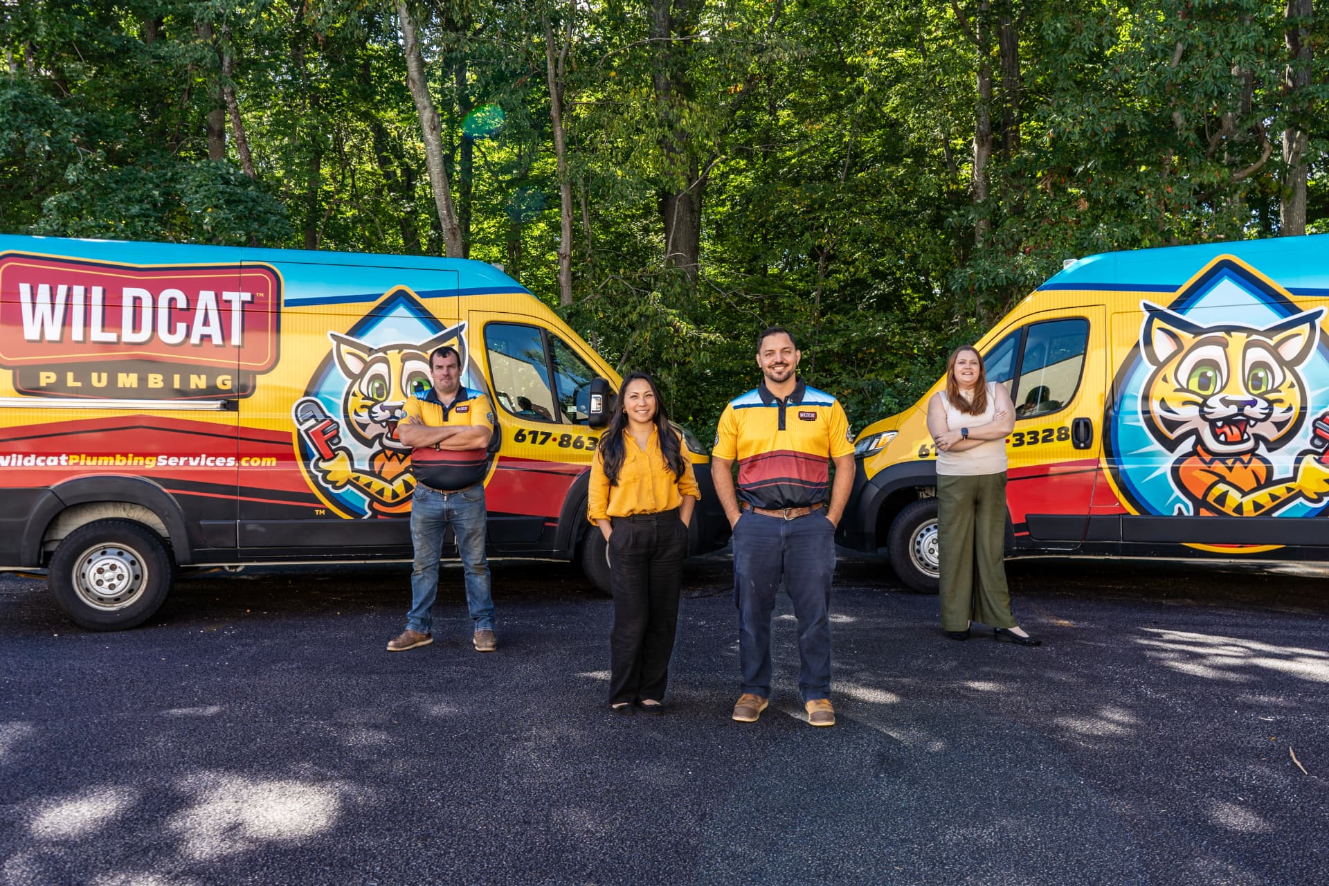 The Wildcat Plumbing team standing in front of two Wildcat service vans